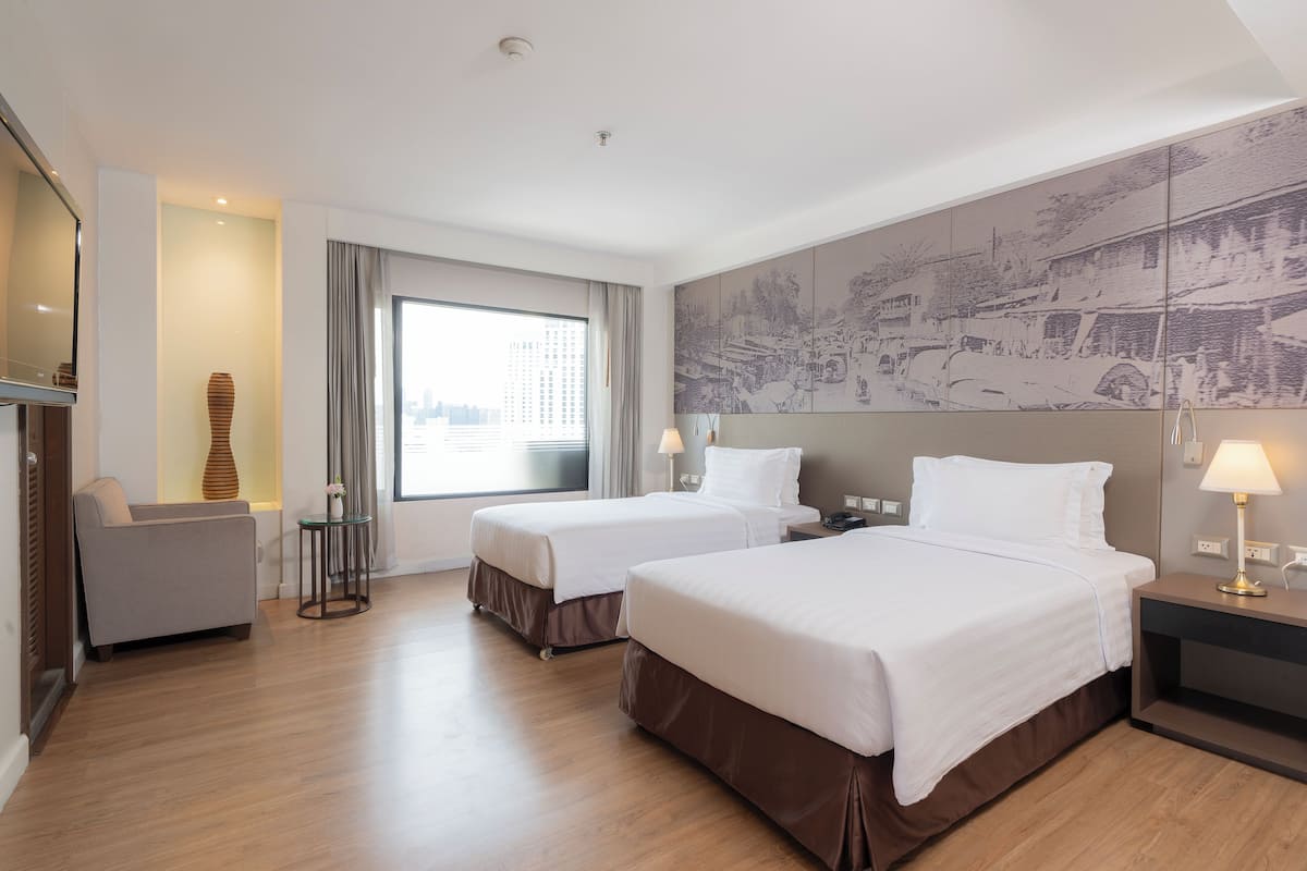 A hotel room with two beds, a sofa, a large window, and a cityscape mural.