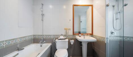 A modern bathroom with a bathtub, toilet, sink, and glass-enclosed shower.
