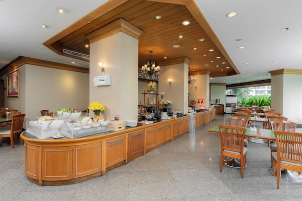 A spacious dining area with wooden furniture, a central buffet counter, and a chandelier. - Grand Diamond Suite (Bangkok)