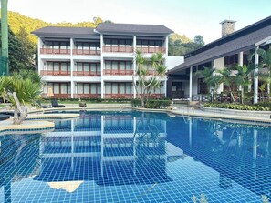 Un hôtel doté d’une grande piscine, de nombreux balcons et d’un espace extérieur couvert agrémenté de palmiers.