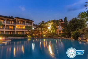 Un hôtel doté d’une piscine, de nombreux balcons et d’une végétation luxuriante.