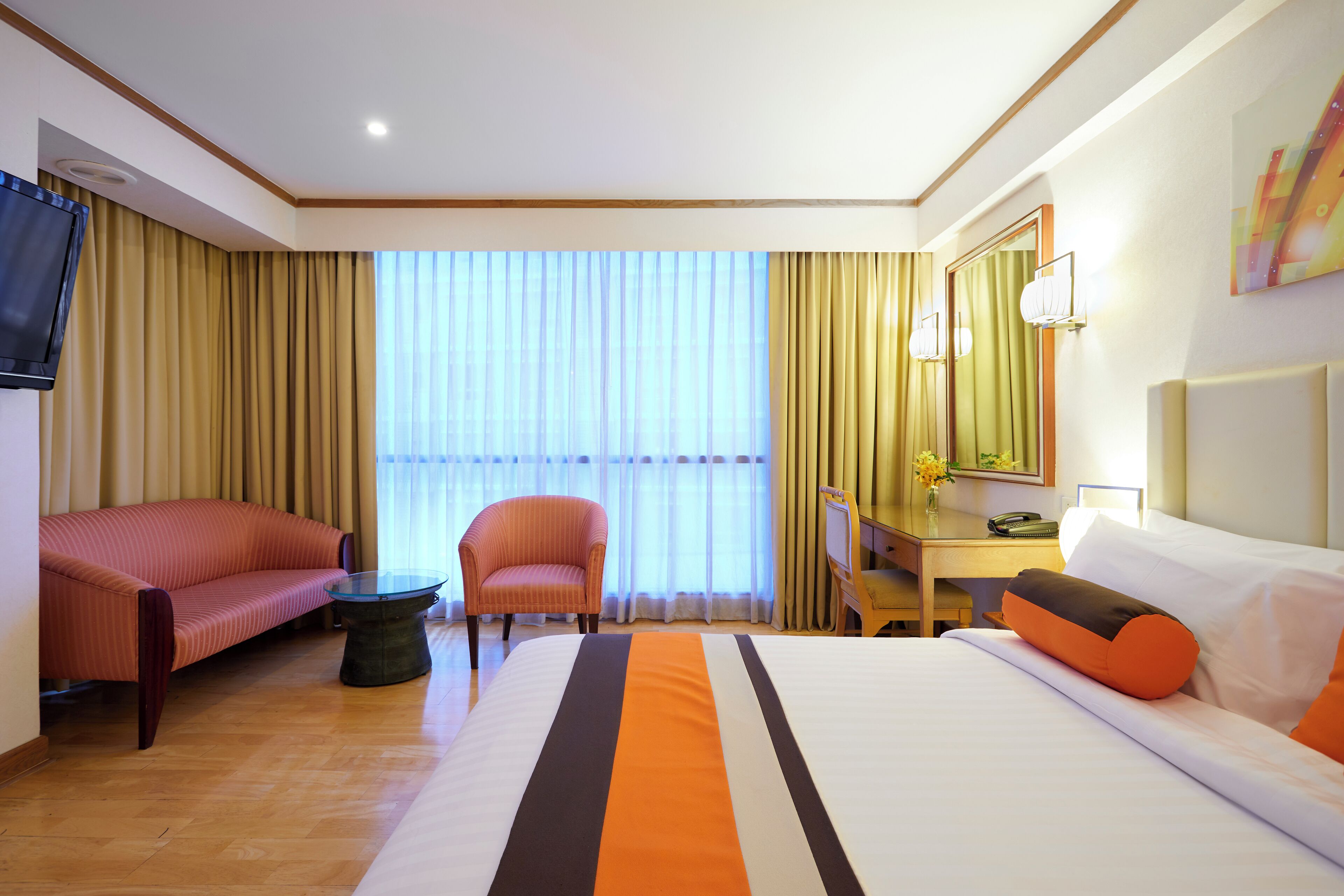 Une chambre d’hôtel comprenant un lit, un canapé, une chaise, un bureau et un téléviseur.