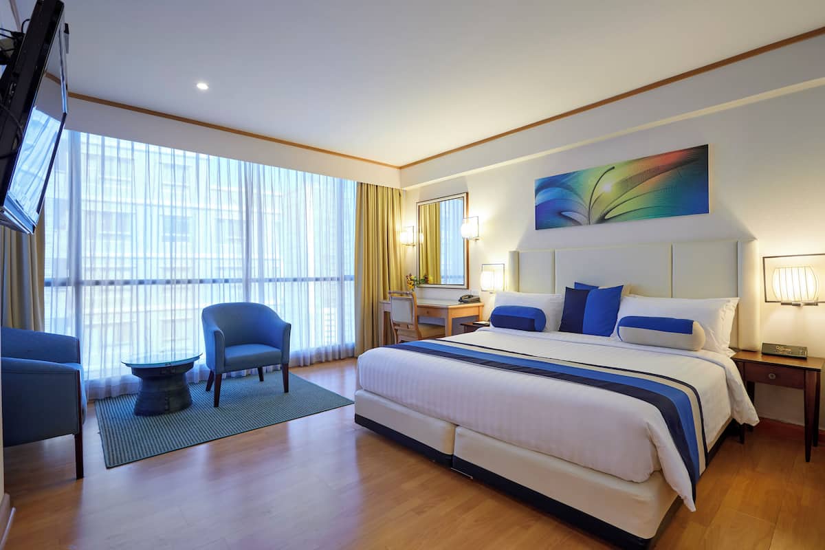 Une chambre d’hôtel avec un grand lit, un bureau, une chaise et un téléviseur.