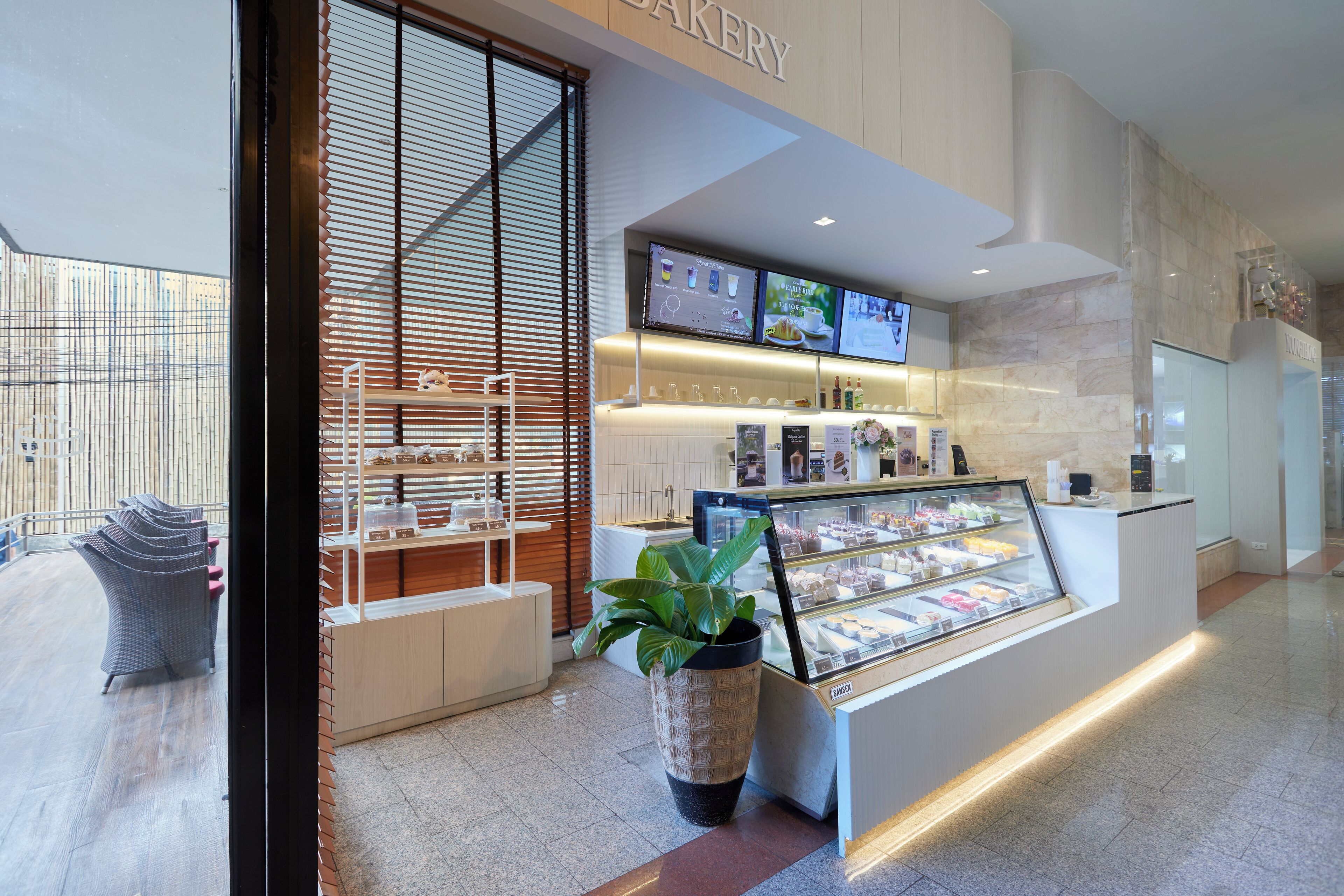 Een bakkerij met een vitrine, een digitaal menu en een zithoek.