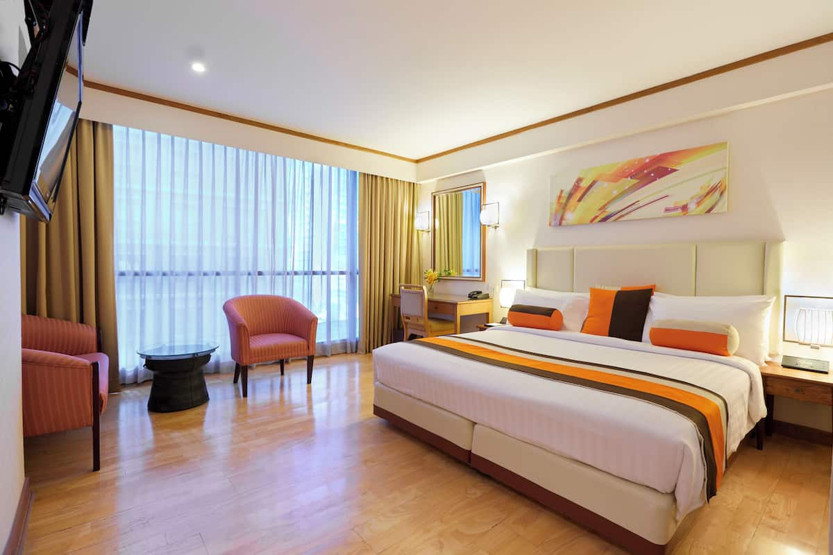 Une chambre d’hôtel avec un grand lit, un bureau, une chaise, une télévision et une grande fenêtre avec des rideaux.