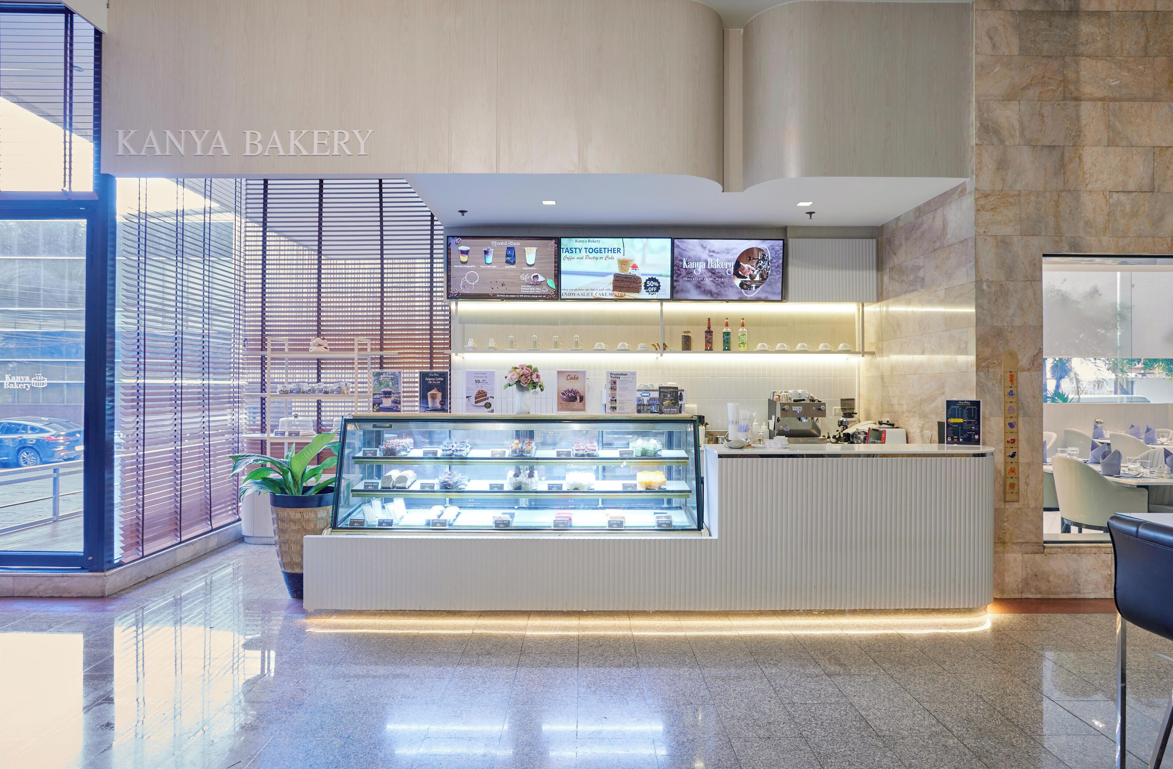 L'intérieur d'une boulangerie, avec un présentoir, un comptoir et des panneaux affichant le menu.