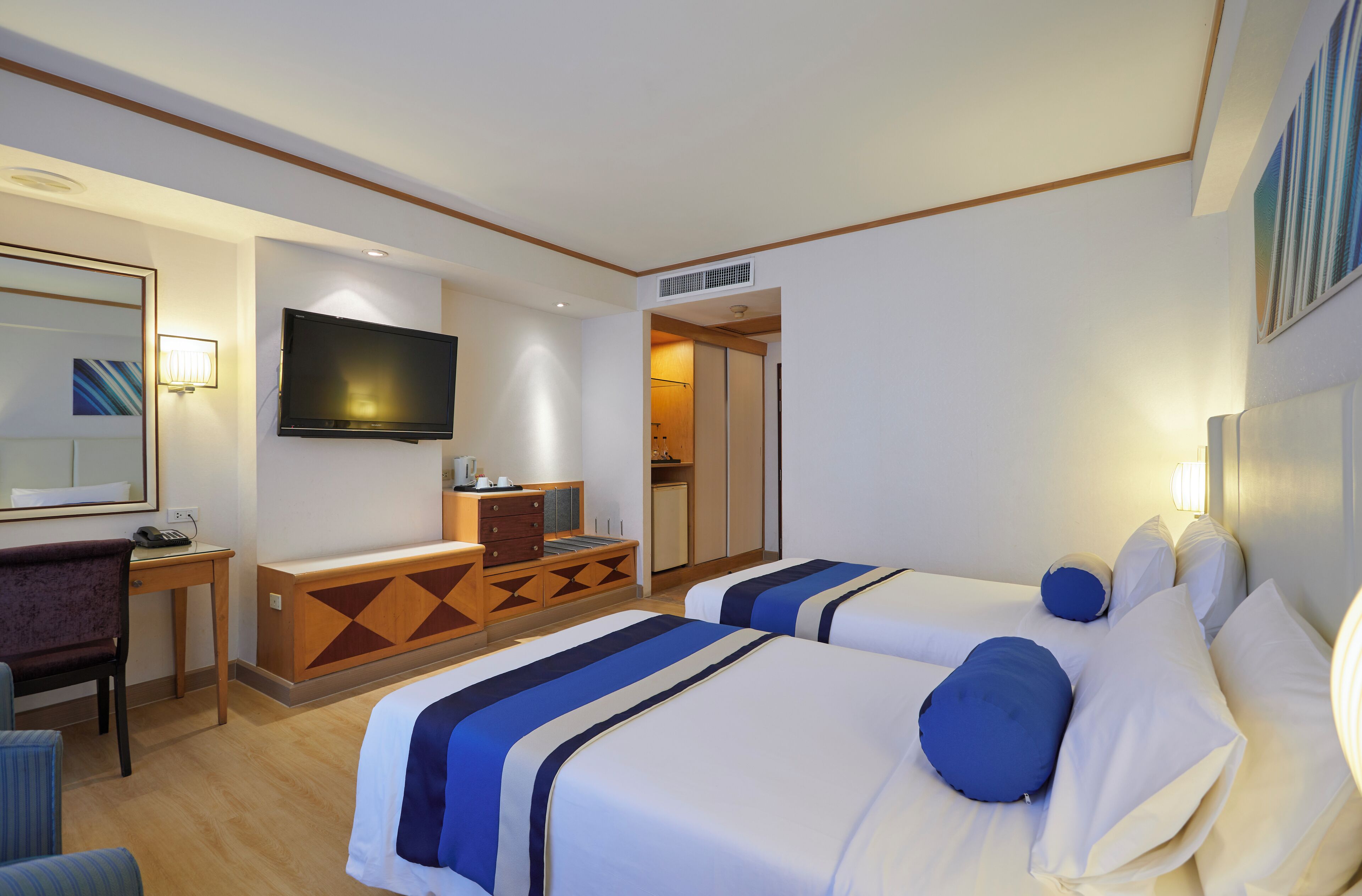 Een hotelkamer met twee bedden, een televisie, een bureau en een stoel.