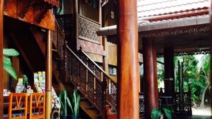 A wooden interior with a staircase, large columns, and a tiled ceiling. - Baan Thai Resort (Chiang Mai)