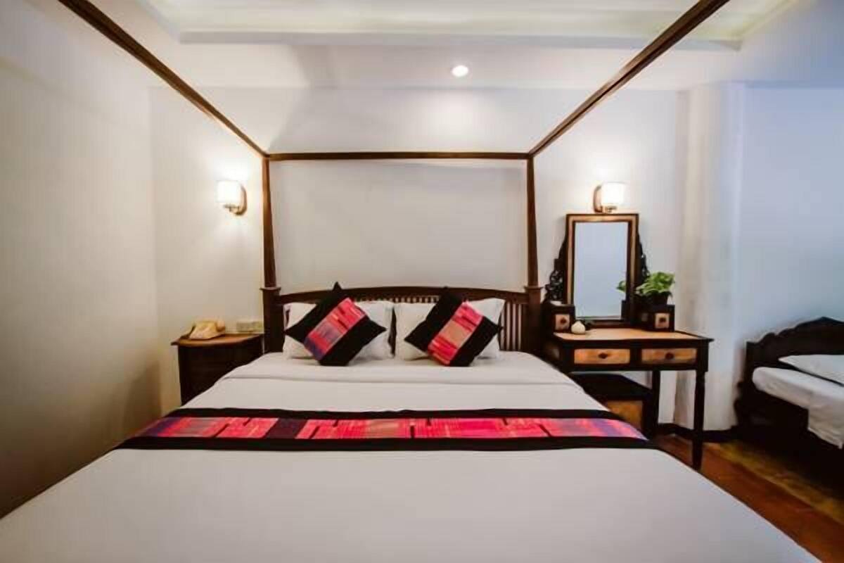 A hotel room with a four-poster bed, bedside tables, a mirror, and a nightstand.
