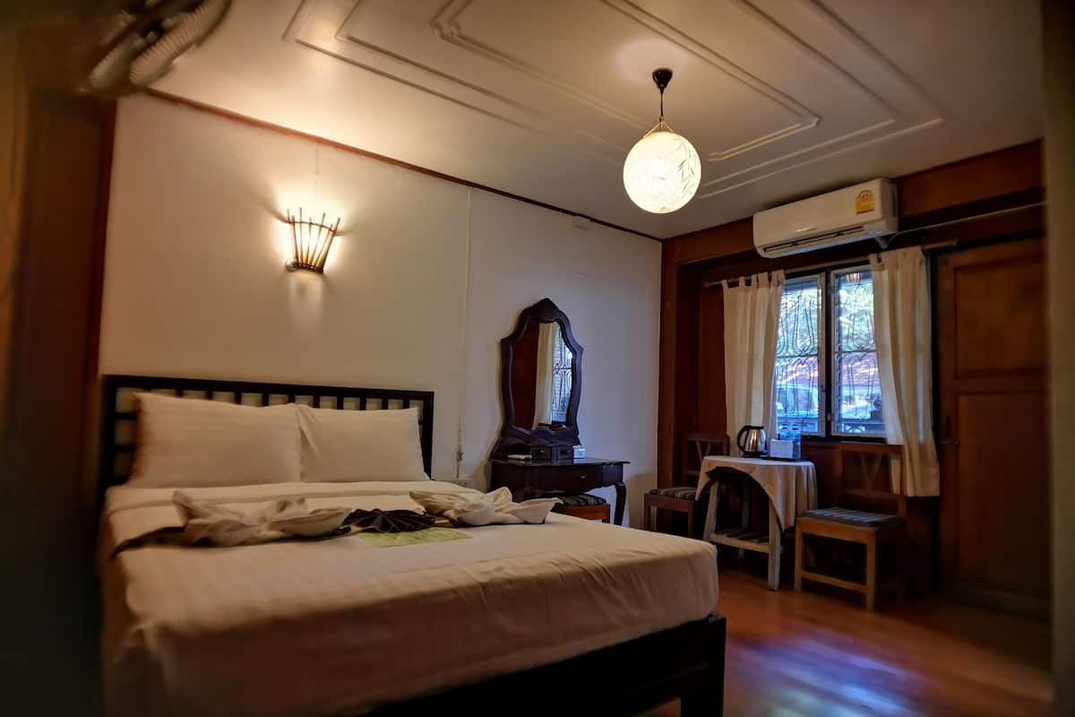 A hotel room with a bed, bedside table, mirror, and a small table with a chair.