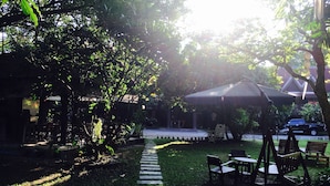 A garden area with a paved walkway, wooden benches, and a covered seating area. - Baan Thai Resort (Chiang Mai)
