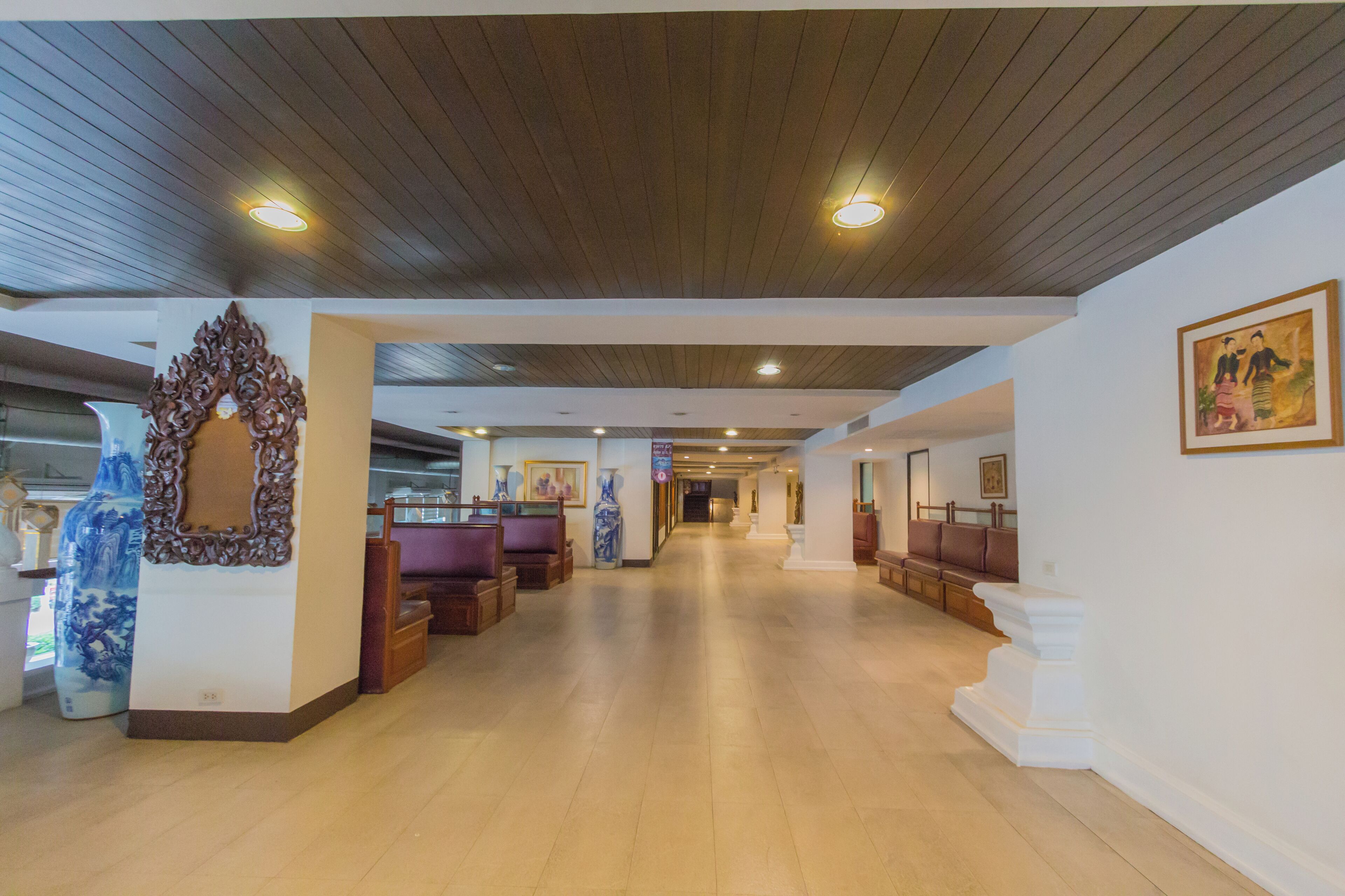 Um hall amplo com teto de madeira, balcão de recepção e áreas de estar.