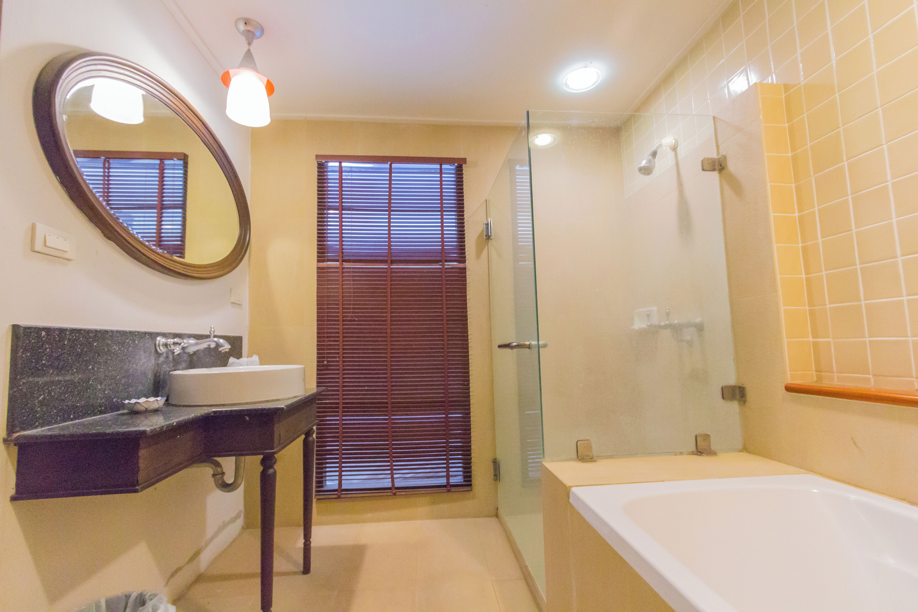 A bathroom with a vanity, sink, mirror, and bathtub.