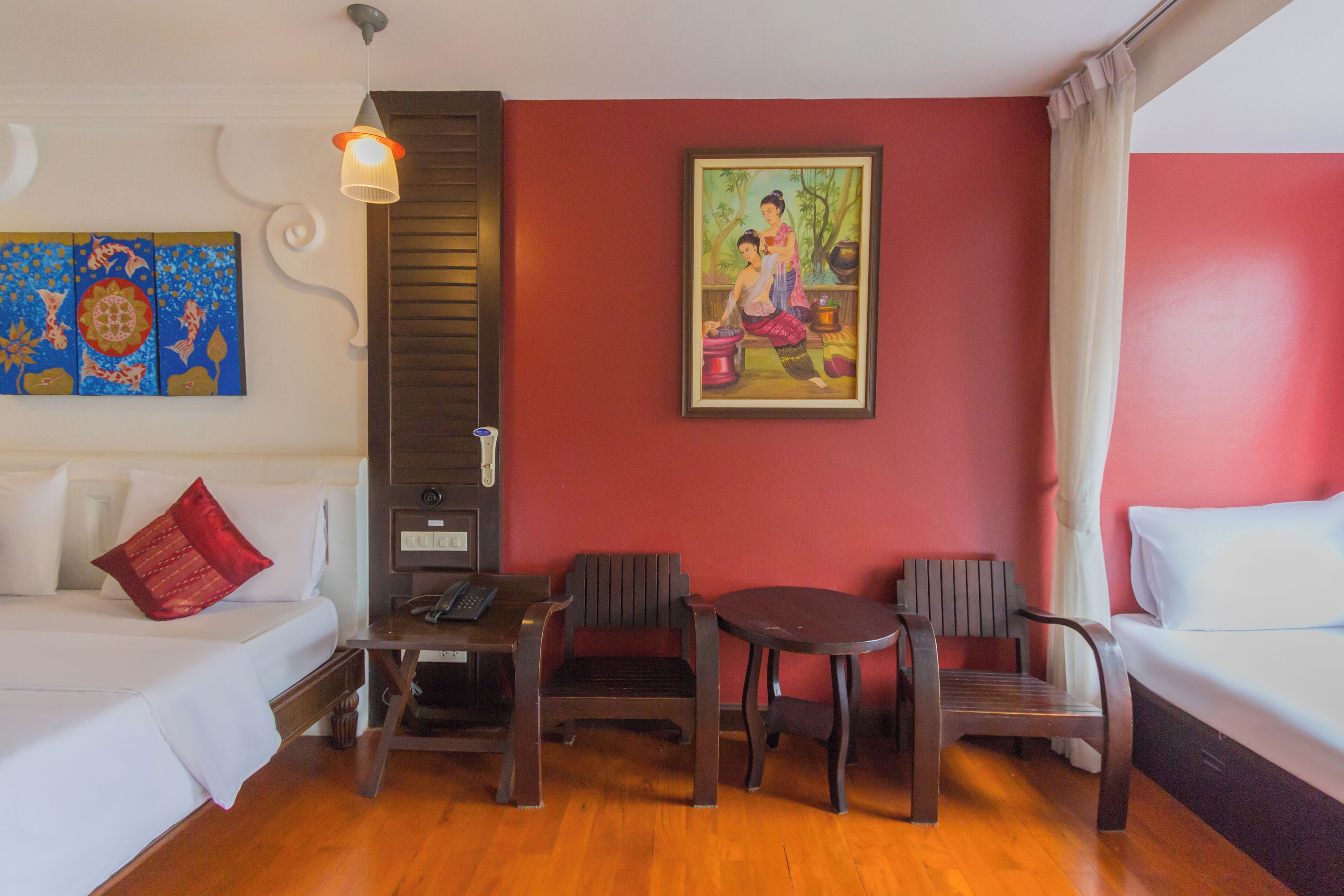 A hotel room with a bed, a desk, two chairs, a table, a painting, and a telephone on the desk.