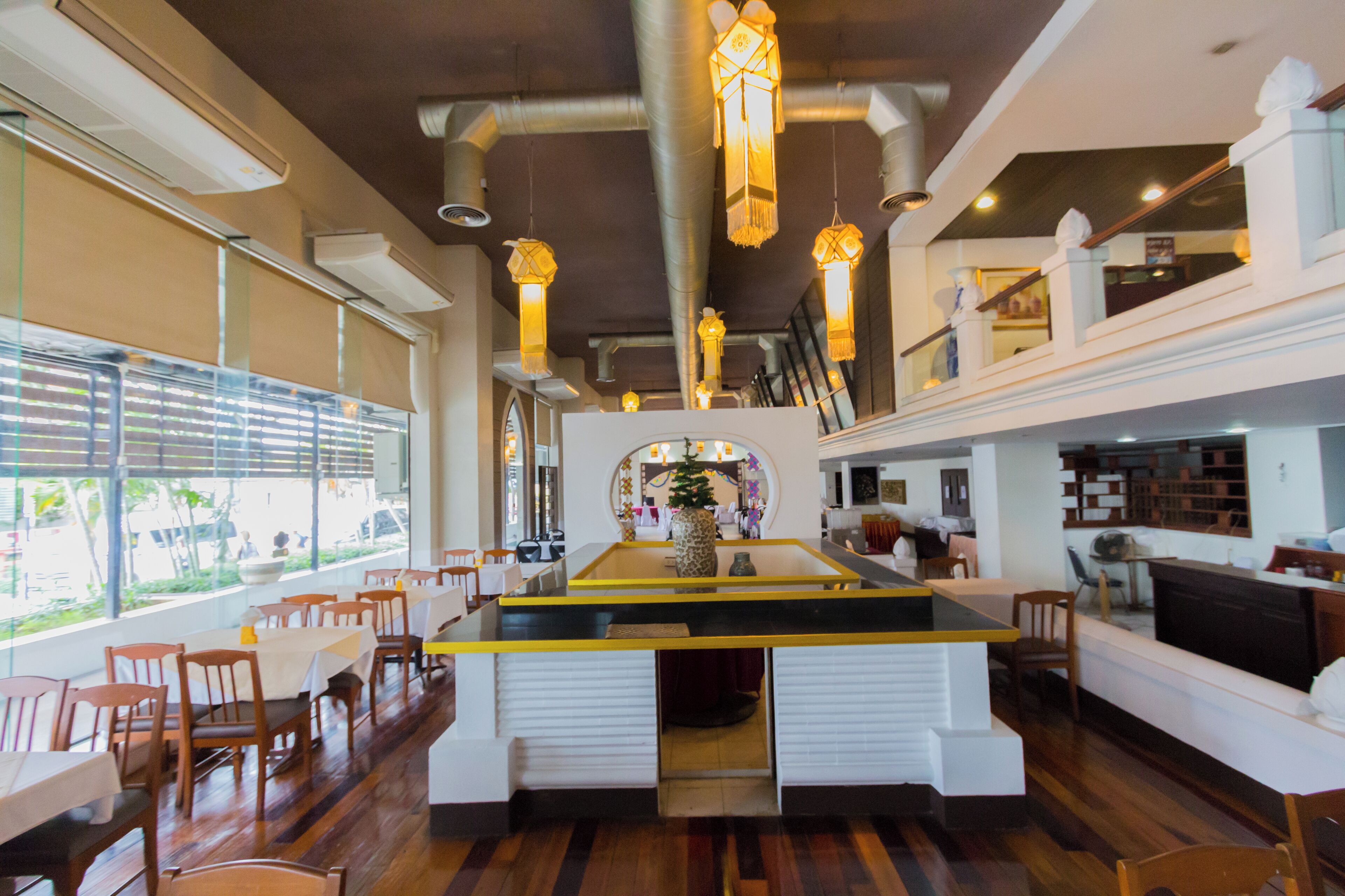 A restaurant with a central island, wooden flooring, and hanging lanterns.