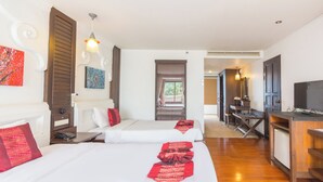 Een hotelkamer met twee bedden, een bureau, een televisie en een raam.