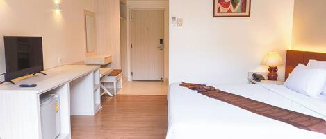 A hotel room with a bed, a desk, a television, a lamp, and a painting on the wall.