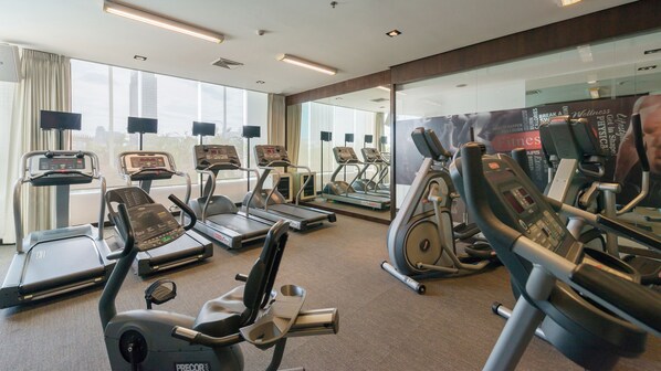 Un gimnasio con cintas de correr, elípticas y bicicletas estáticas.