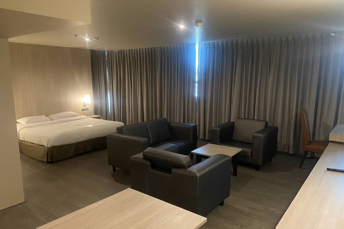 A modern hotel room with a bed, two sofas, a coffee table, and a desk.