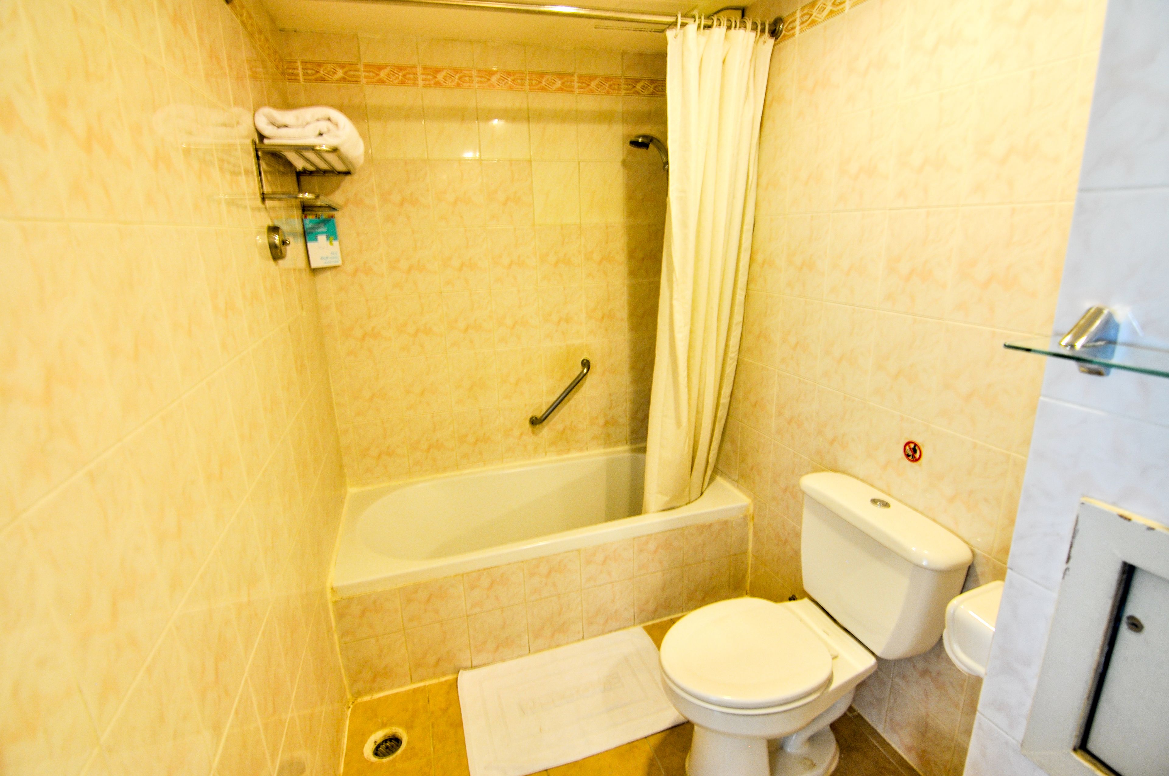 Un baño con bañera, inodoro y cortina de ducha.