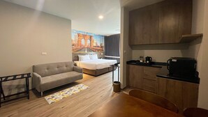A compact hotel room with a bed, a sofa, a small dining table, and a kitchenette. - Manhattan Bangkok (Bangkok)