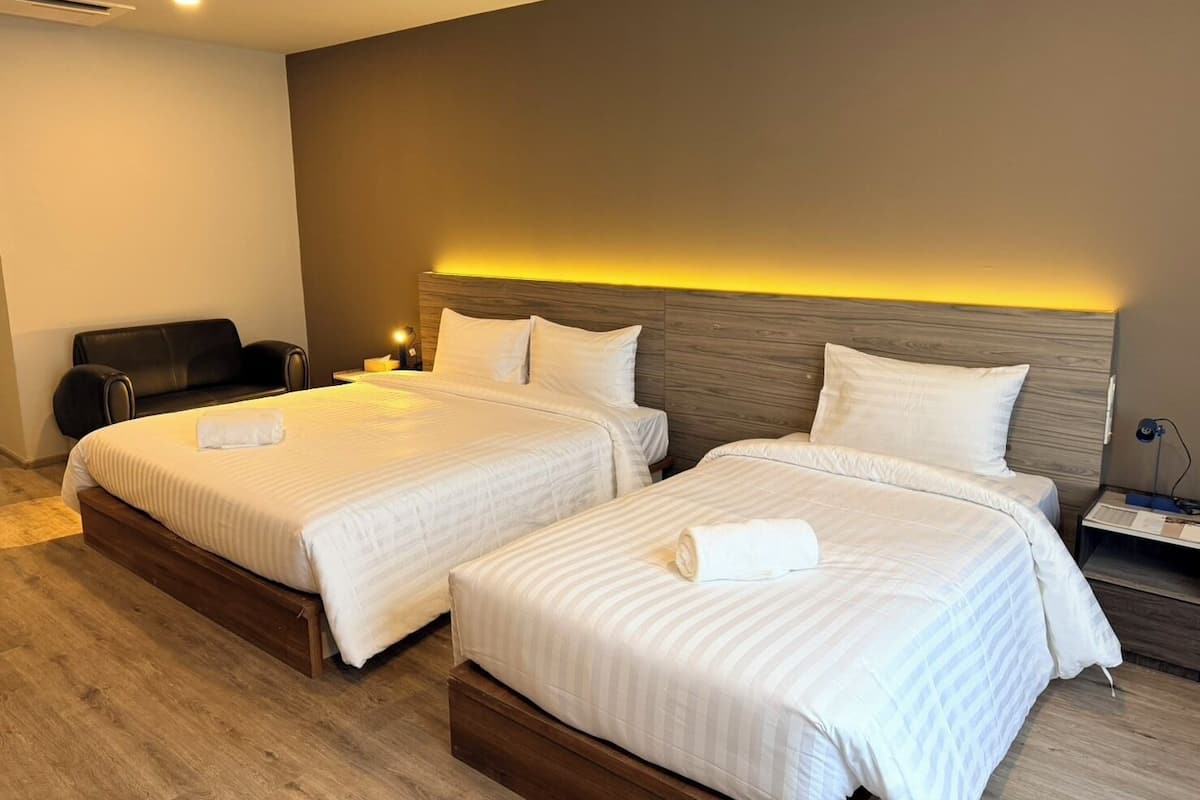 Habitación de hotel con dos camas, un sofá y una televisión.