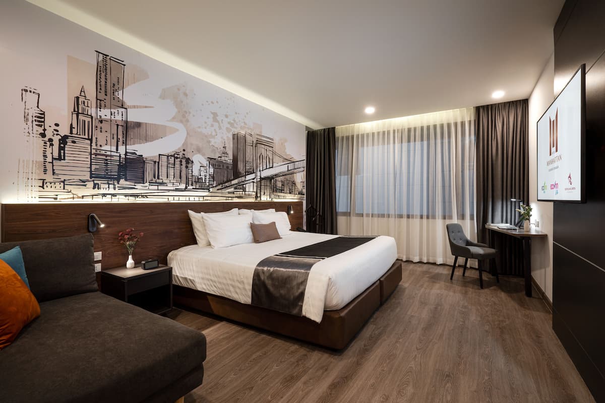 Habitación de hotel moderna con una cama grande, un sofá, un escritorio y un mural con vistas a la ciudad.