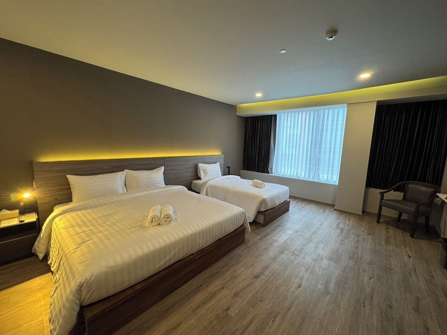 Une chambre d’hôtel avec deux lits, un plancher en bois, un bureau et une chaise.