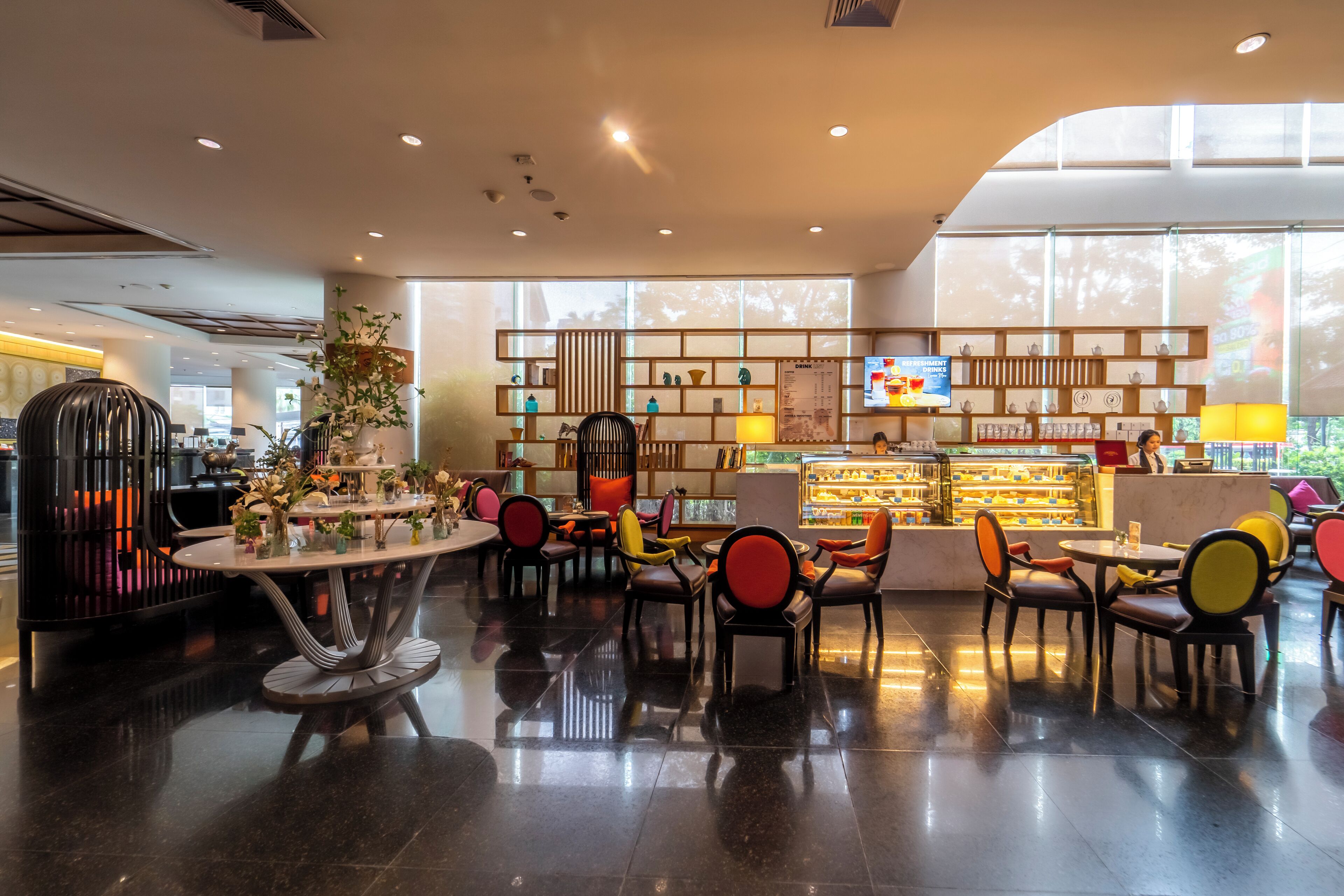 Un interior moderno con una zona de estar central, un mostrador de exhibición y una pantalla de proyección.