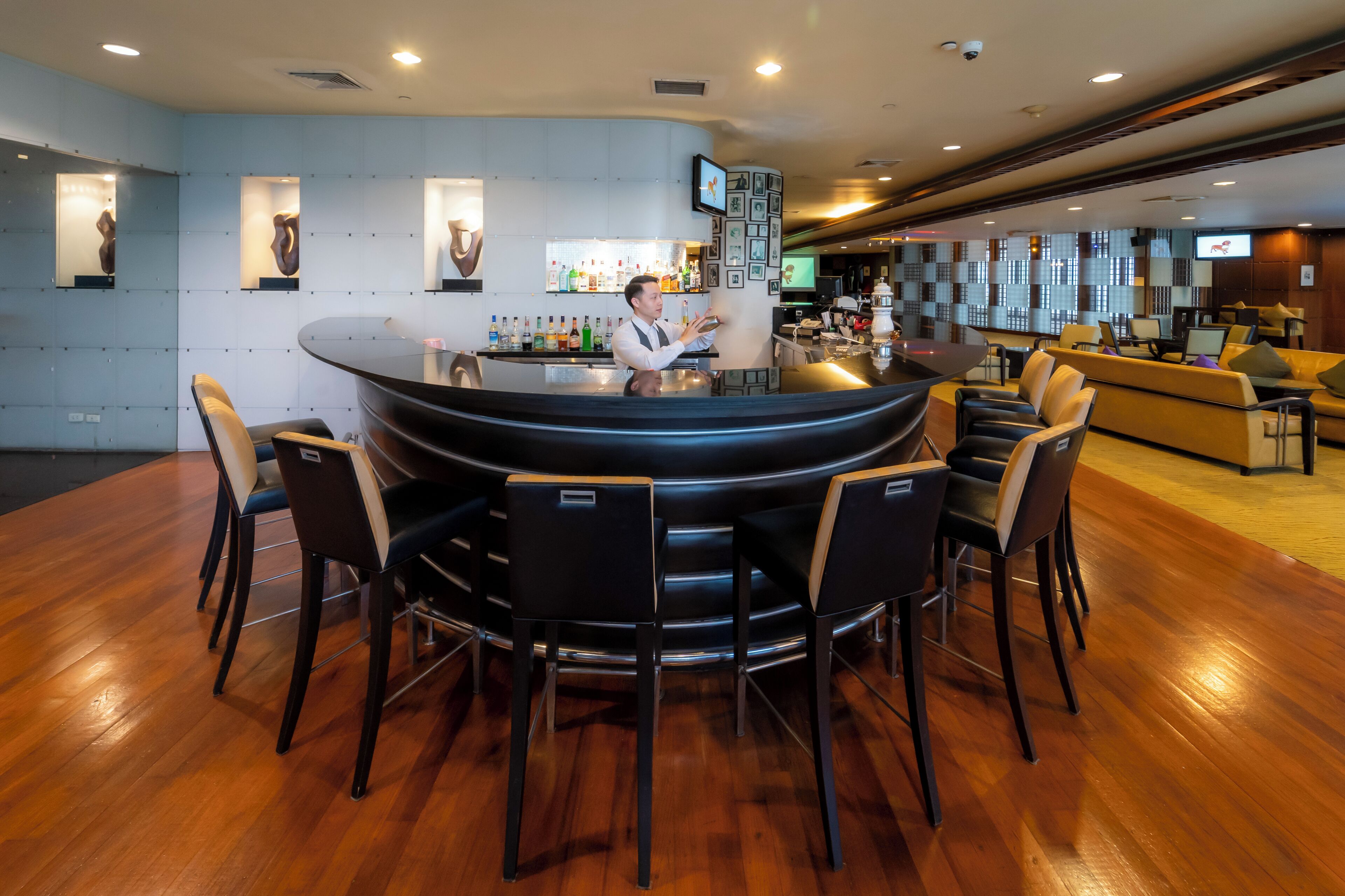 A modern bar area with a round bar, multiple seating options, and a well-stocked liquor display.