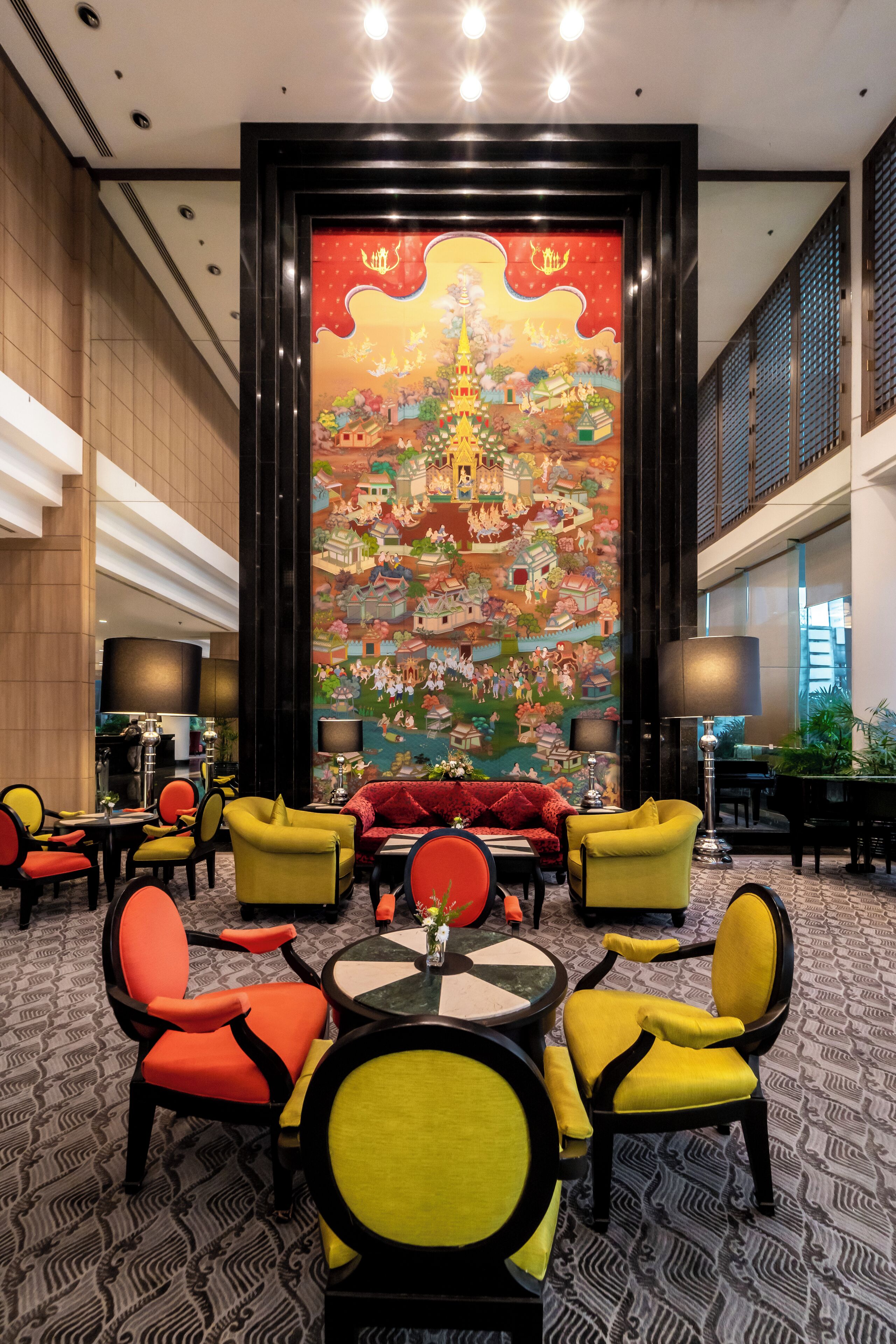 A lobby with a large mural, yellow and red chairs, and a modern interior design.