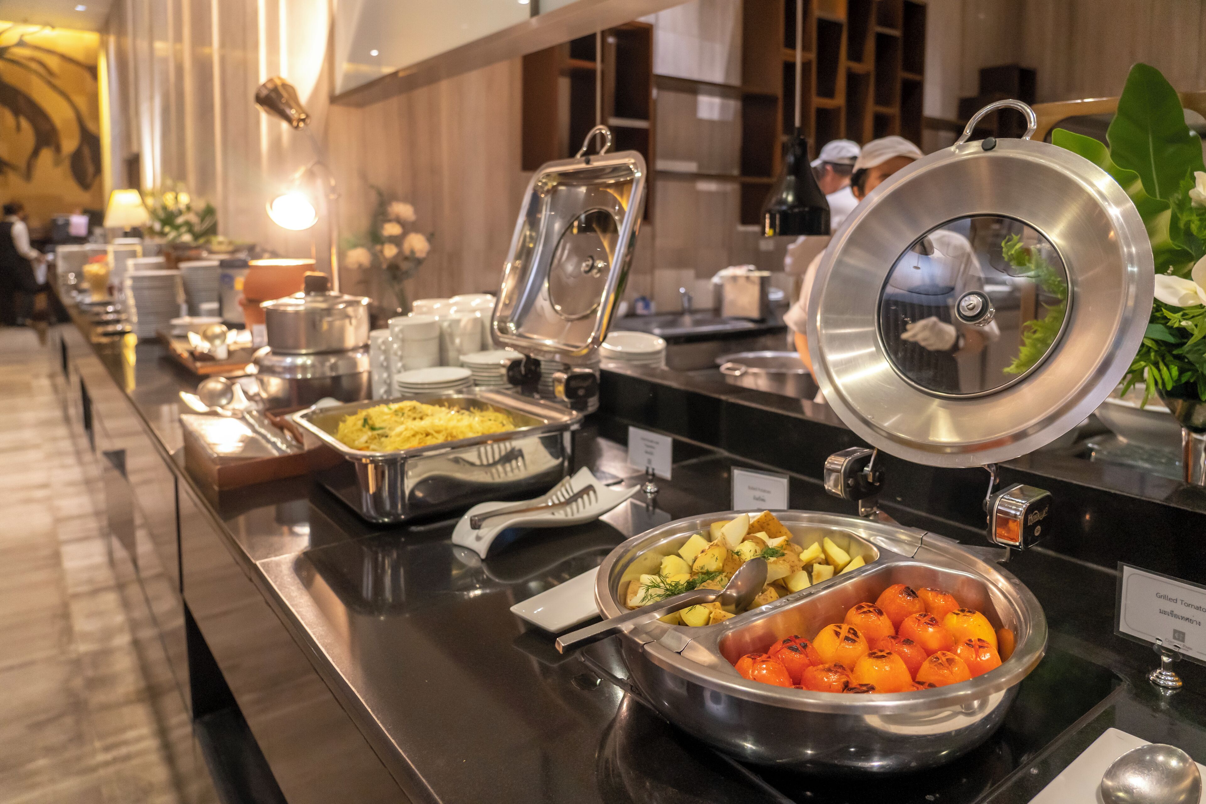 A buffet with various food items, including roasted potatoes, grilled tomatoes, and other dishes.