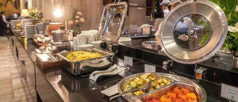 A buffet with various food items, including roasted potatoes, grilled tomatoes, and other dishes.