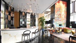 A modern bar area with a marble countertop, bar stools, and a large potted plant. - Century Park Hotel (Bangkok)