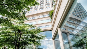 A modern building with a large glass facade, a central fountain, and lush greenery. - Century Park Hotel (Bangkok)