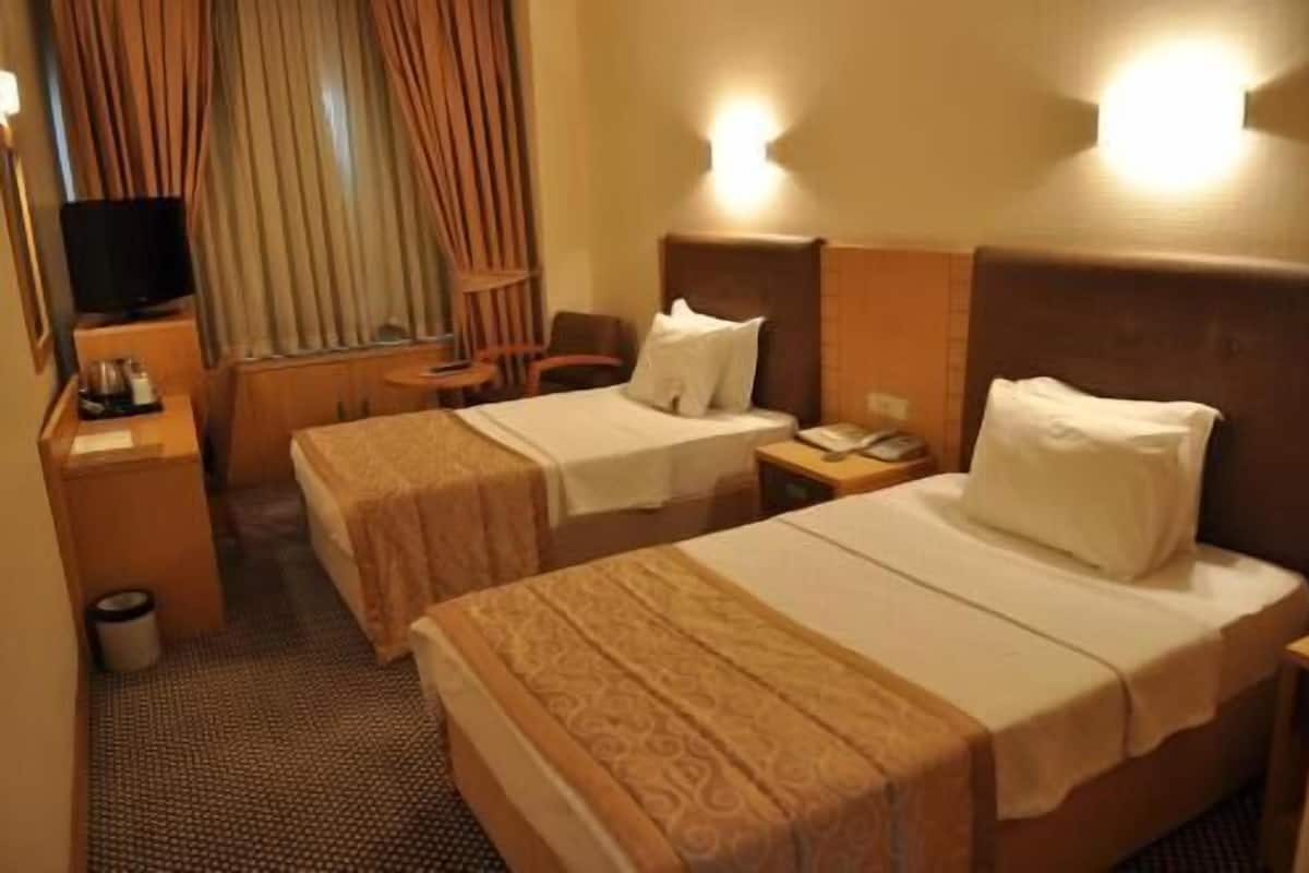 A hotel room with two beds, a television, a small table, and a chair.