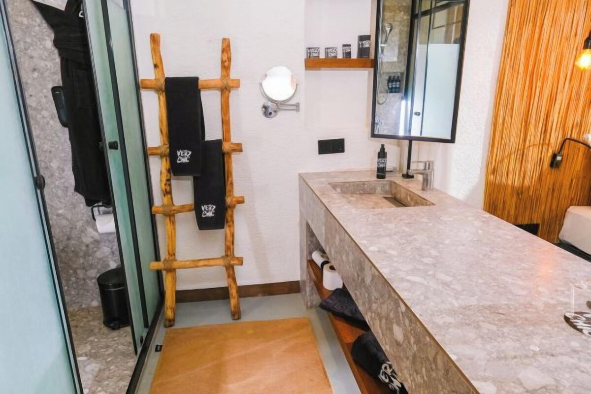 A bathroom with a marble sink, a mirror, a towel rack, and a small shelf with toiletries.