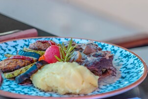 Un plato con diversos alimentos, incluyendo carne, verduras y puré de papas.