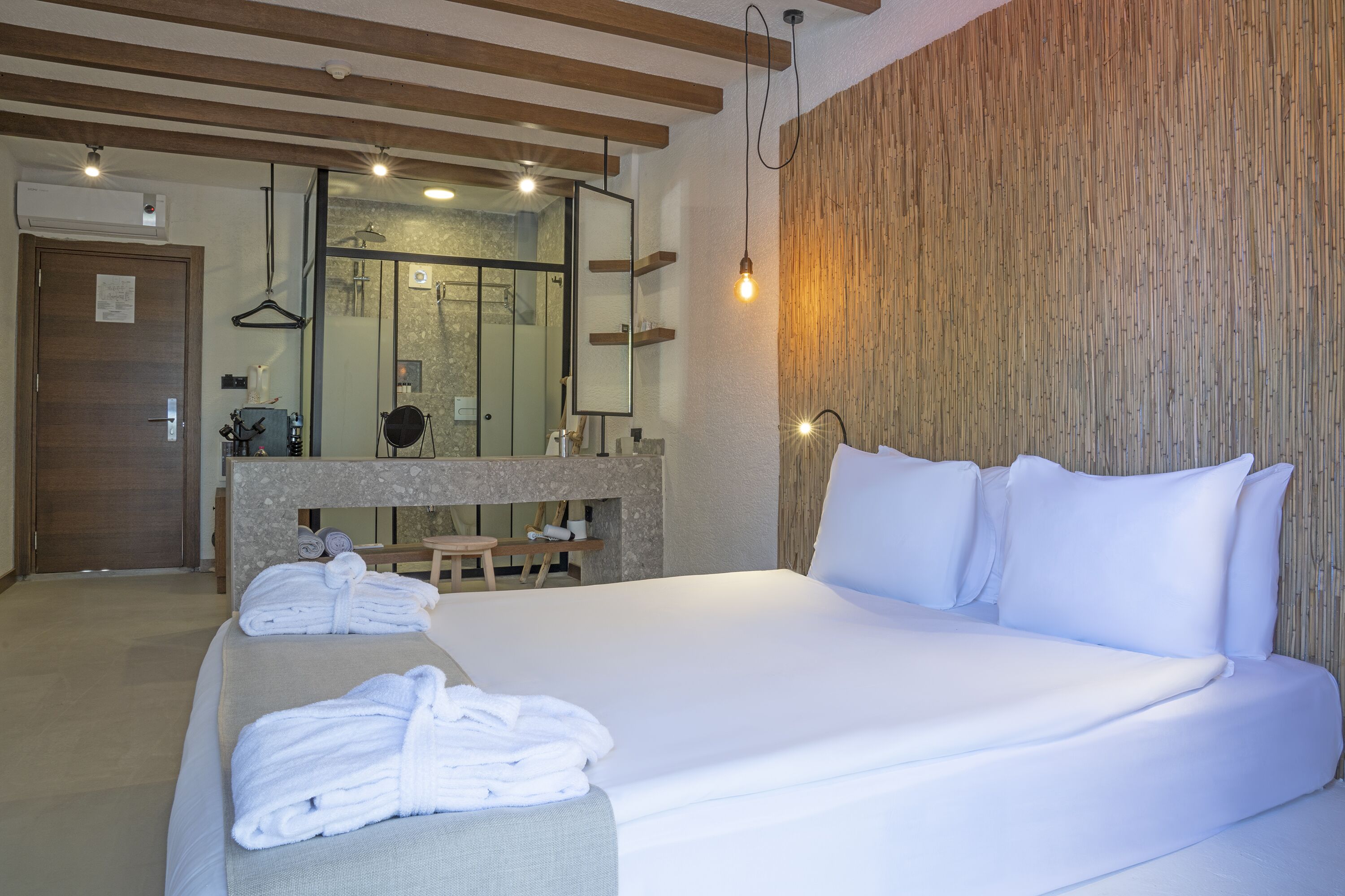 Una habitación de hotel con una cama grande, techo de madera, baño con espejo y barra para toallas.