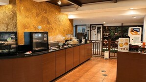 A hotel lobby with a reception desk, a coffee machine, and a menu stand.