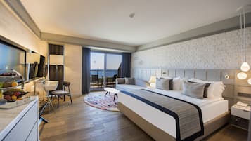 A modern hotel room with a large bed, a dining area, and a view of the outdoors.