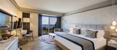 Una habitación de hotel moderna con una cama grande, un área de comedor y vistas al exterior.