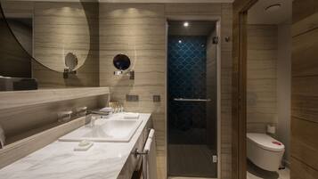 A modern bathroom with a marble vanity, a glass-enclosed shower, and a toilet with a decorative cover.