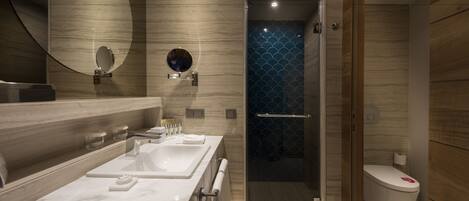 A modern bathroom with a marble vanity, a glass-enclosed shower, and a toilet with a decorative cover.