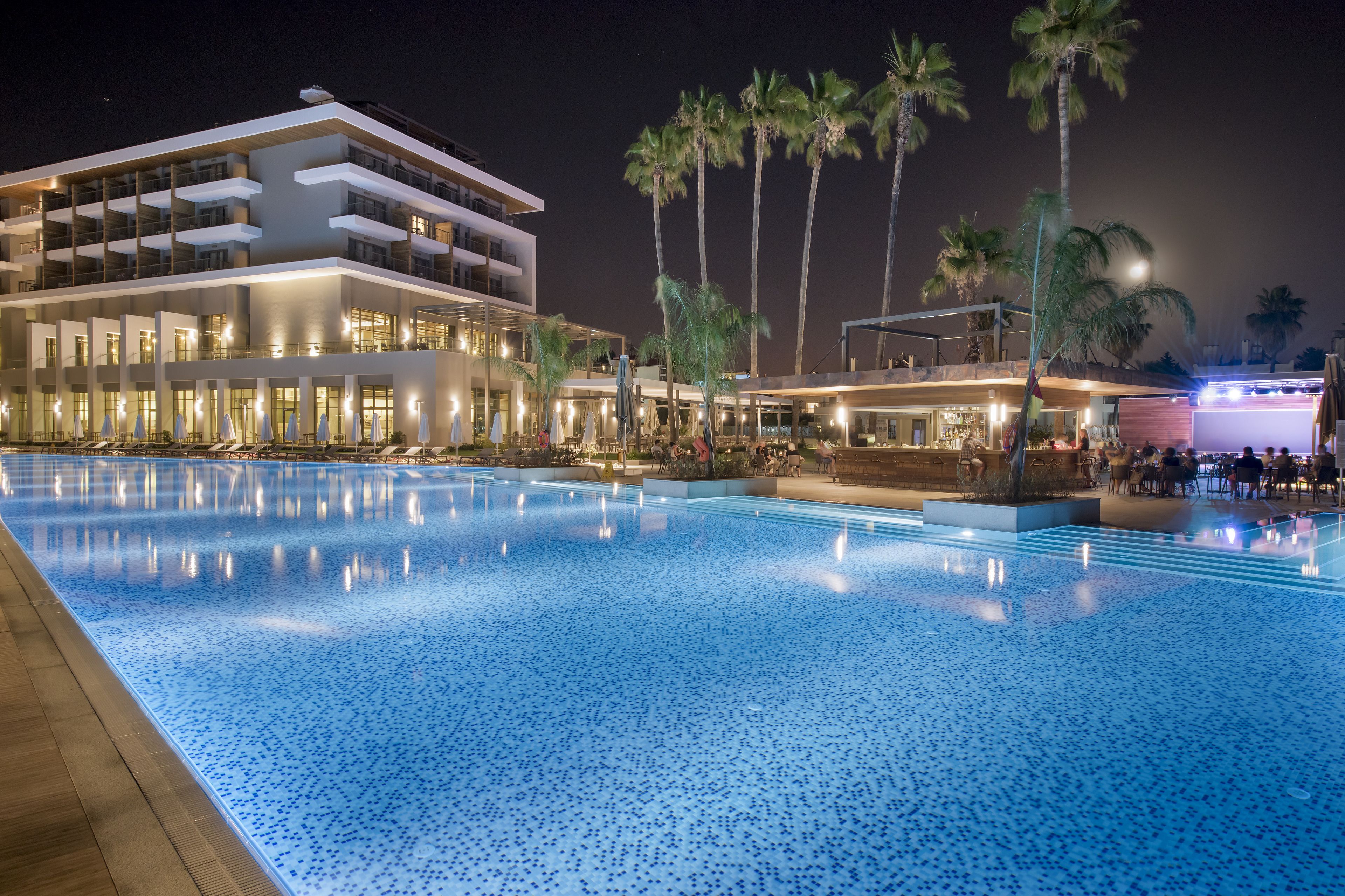 Una piscina con un hotel moderno al fondo.