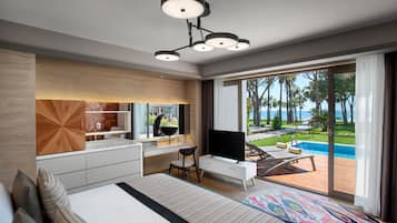 A modern hotel room with a large bed, a desk with a flat-screen TV, a dining area, and a view of a pool and tropical landscape.