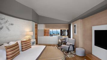 A modern hotel room with a large bed, a desk, a chair, and a TV.