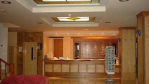 A hotel lobby with a reception desk, a red sofa, and a glass-top table. - Imperial Hotel (Kos)