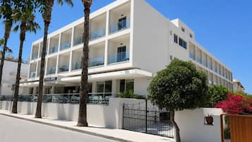 Ein mehrstöckiges Hotel mit Balkonen, Palmen und einem verschlossenen Eingang.