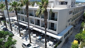 A multi-story hotel with balconies, palm trees, and a clear view of the surrounding cityscape. - Imperial Hotel (Kos)